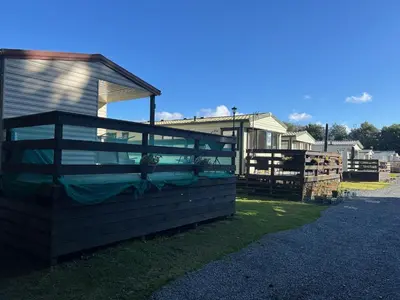 a building with a fence next to a house at Creebridge Caravan Park in Newton Stewart