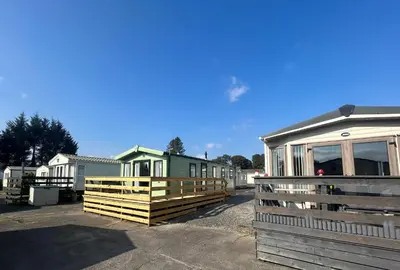 a row of mobile homes parked next to a fence at Creebridge Caravan Park in Newton Stewart