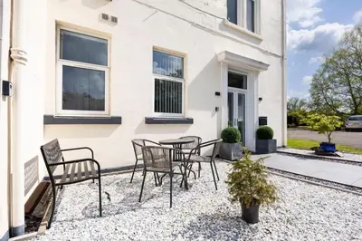 a patio with chairs and a table in front of a house at 2 Bedroom in the Heart of Loch Lomond in Balloch