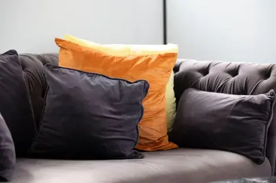 an orange and black pillow on a leather couch at 2 Bedroom in the Heart of Loch Lomond in Balloch