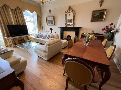 a living room with a table and a couch and a fireplace at Wonderful 3 Bed West End Flat in Glasgow