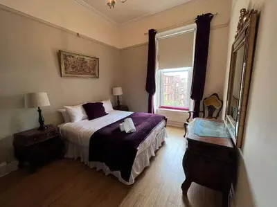 a bedroom with a bed and a large window at Wonderful 3 Bed West End Flat in Glasgow