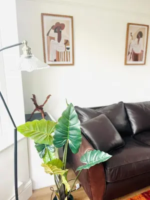 a living room with a leather couch and a plant at Lovely spacious home near station in Moffat