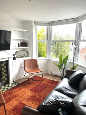 a living room with a leather couch and a chair at Lovely spacious home near station in Moffat