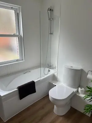 a white bathroom with a toilet and a bath tub at Lovely spacious home near station in Moffat