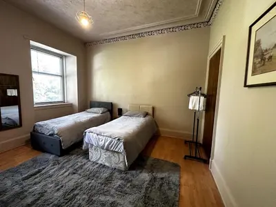 a bedroom with two beds and a rug at Cheerful 5 Bedroom House Close to Central West End and Parking in Glasgow