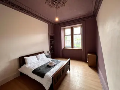 a bedroom with a bed and a large window at Cheerful 5 Bedroom House Close to Central West End and Parking in Glasgow