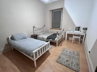 a bedroom with two beds and a desk with a laptop at Cheerful 5 Bedroom House Close to Central West End and Parking in Glasgow