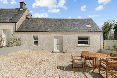 a cottage with a table and chairs in front of it at Luxury 2 Bed cottage in Killin in Killin