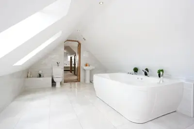 a white bathroom with a large tub in a attic at Greenknowes Entire Private Estate in Kelty