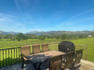a table and chairs on a deck with a view of a field at Ardvenhor in Gartocharn