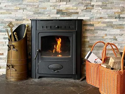 a black stove with a fire in a brick wall at Ardvenhor in Gartocharn