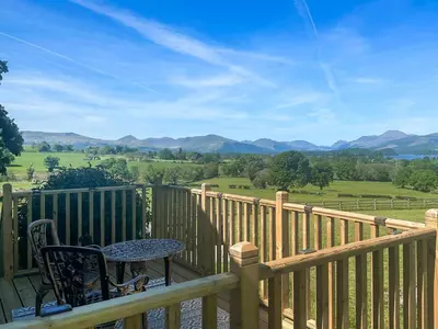 a table and chair on a porch with a view of mountains at Ardvenhor in Gartocharn