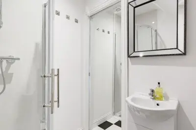 a white bathroom with a sink and a shower at Converted Historical Stone Coach House in Glasgow