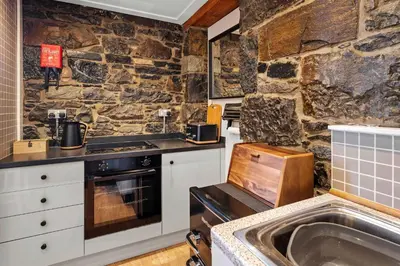 a kitchen with a stone wall and a sink at Stunning 1Bedroom Central Apartment in Oban
