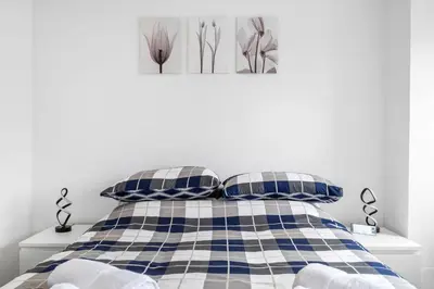 a bedroom with a bed with blue and white plaid pillows at Modern & Central 1BR Flat with Sky TV in Oban