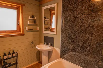 a bathroom with a sink and a mirror and a tub at Lodge 2 in Stirling