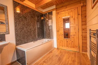 a bathroom with a tub and a wooden floor at Lodge 6 in Stirling