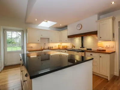 a kitchen with white cabinets and a black counter top at The Stables in Thornhill
