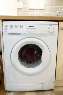 a white washing machine under a counter in a kitchen at Modern 1BR Apartment - Close to ferry terminal with free parking in Oban