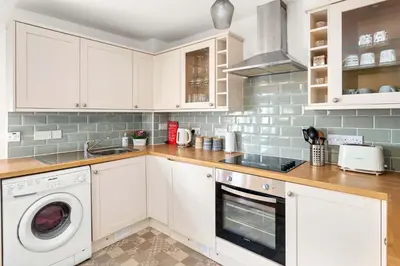 a kitchen with white cabinets and a washer and dryer at Modern 1BR Apartment - Close to ferry terminal with free parking in Oban