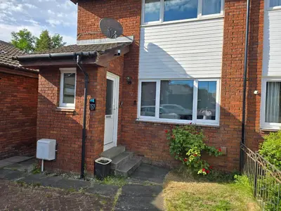 a brick house with a cat sitting in a window at My Glasgow House Robroyston in Hogganfield