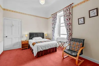 a bedroom with a bed and a chair and a window at Rosemount in Campbeltown