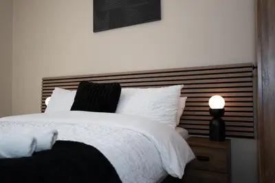 a bedroom with a bed with a wooden headboard at The White House near Edinburgh in Bathgate