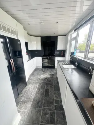 a kitchen with white cabinets and a tile floor at Galaxy Glasgow 67 in Cardonald