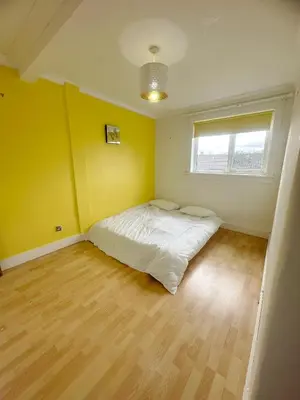a bedroom with a bed in a room with yellow walls at Galaxy Glasgow 67 in Cardonald
