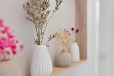 three white vases sitting on a shelf with flowers at Lovely Haymarket Apartment - Central Edinburgh in Edinburgh