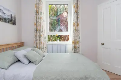 a bedroom with a large white bed with a window at Lovely Haymarket Apartment - Central Edinburgh in Edinburgh