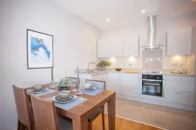 a kitchen with a wooden table and a kitchen with white cabinets at Stylish 2-Bed Apartment Near Glasgow Green in Glasgow