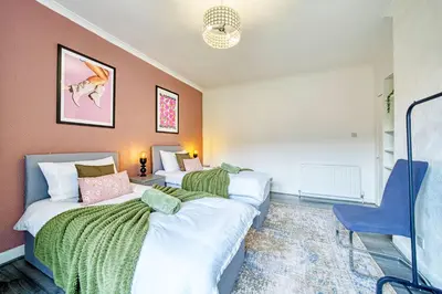 a bedroom with two beds and a blue chair at 2BR Shawlands Free Parking Great Location in Glasgow