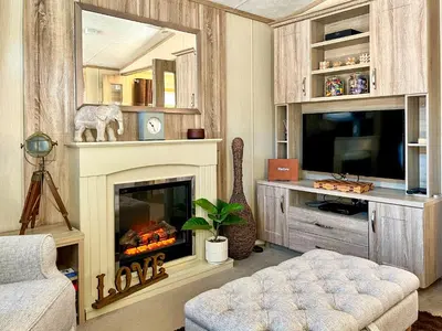 a living room with a fireplace and a tv at Burnside Lodge in Auchterarder