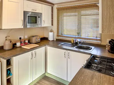a kitchen with white cabinets and a sink at Burnside Lodge in Auchterarder