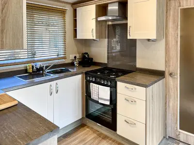 a kitchen with white cabinets and a stove top oven at Burnside Lodge in Auchterarder