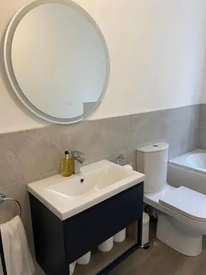 a bathroom with a sink and a mirror and a toilet at Spacious 2 bed sleeps 5 above traditional music pub in Paisley