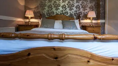 a large wooden bed with two lamps on two tables at Cairndow Stagecoach Inn in Cairndow