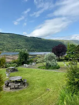 a picnic table in a field next to a lake at Cairndow Stagecoach Inn in Cairndow