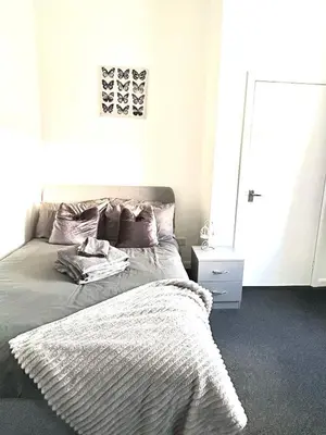 a bedroom with a bed with a blanket and a mirror at Flat 156 at M Rooms in Shotts Station