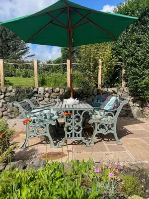 a table and chairs with a green umbrella at Glencairn Cottage in Moffat