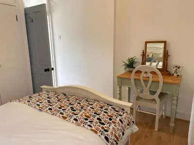 a bedroom with a bed and a desk with a mirror at Glencairn Cottage in Moffat