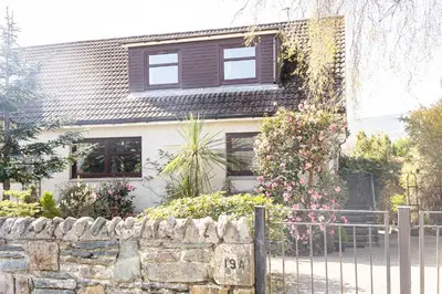 a house with a stone fence in front of it at Birchgate Bothy - Spacious 4 Bedroom Home in Dunoon in Dunoon