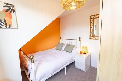 a bedroom with a bed with an orange wall at Birchgate Bothy - Spacious 4 Bedroom Home in Dunoon in Dunoon