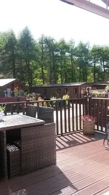 a deck with a table and chairs and a fence at Jasper Lodge in Beautiful Glendevon Country Park Perthshire Scotland in Glendevon