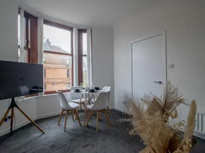 a living room with a table and chairs and a tv at Pass the Keys Stay in Glasgow South in Glasgow