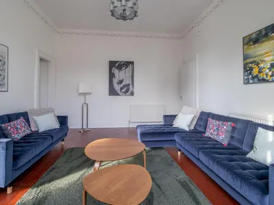 a living room with blue couches and a table at Pass the Keys Victoria Road Queens Park View in Glasgow