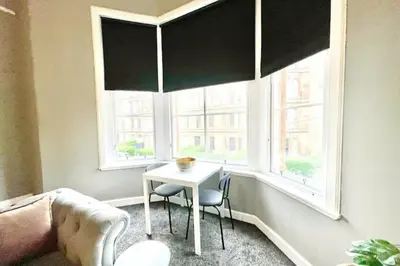 a living room with a table and two windows at Pass the Keys West End Wonder in Glasgow