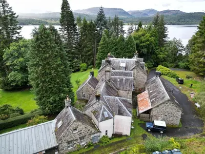 an aerial view of an old house with trees and water at Birch Tree Cottage in Killichonan